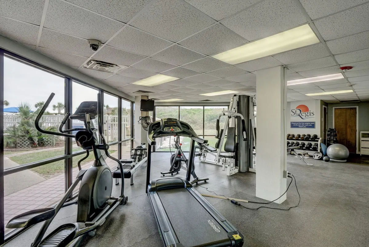 A motivating fitness center with treadmills, elliptical machines, weight training equipment, and expansive windows letting in plenty of natural light. The setup invites guests to pursue fitness routines while enjoying views of the outdoors.