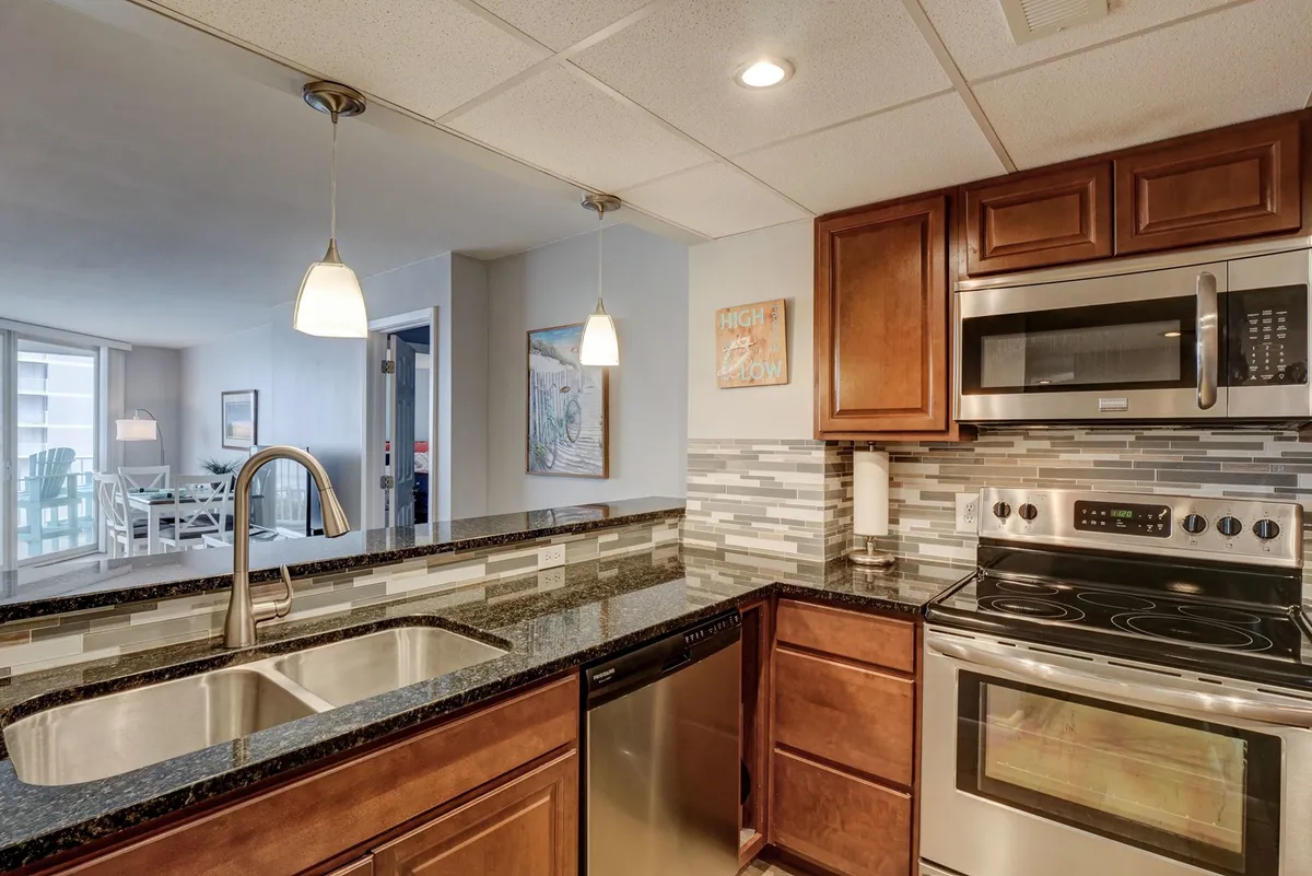 A modern kitchen featuring a central island with a sink, high-end appliances, a decorative backsplash, and pendant lighting. The design is both functional and stylish, ideal for cooking, entertaining, and gathering as a group.
